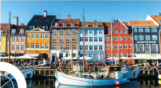 Imagem de edificios residenciáis coloridos à beira rio, com barcos, em Copenhaga